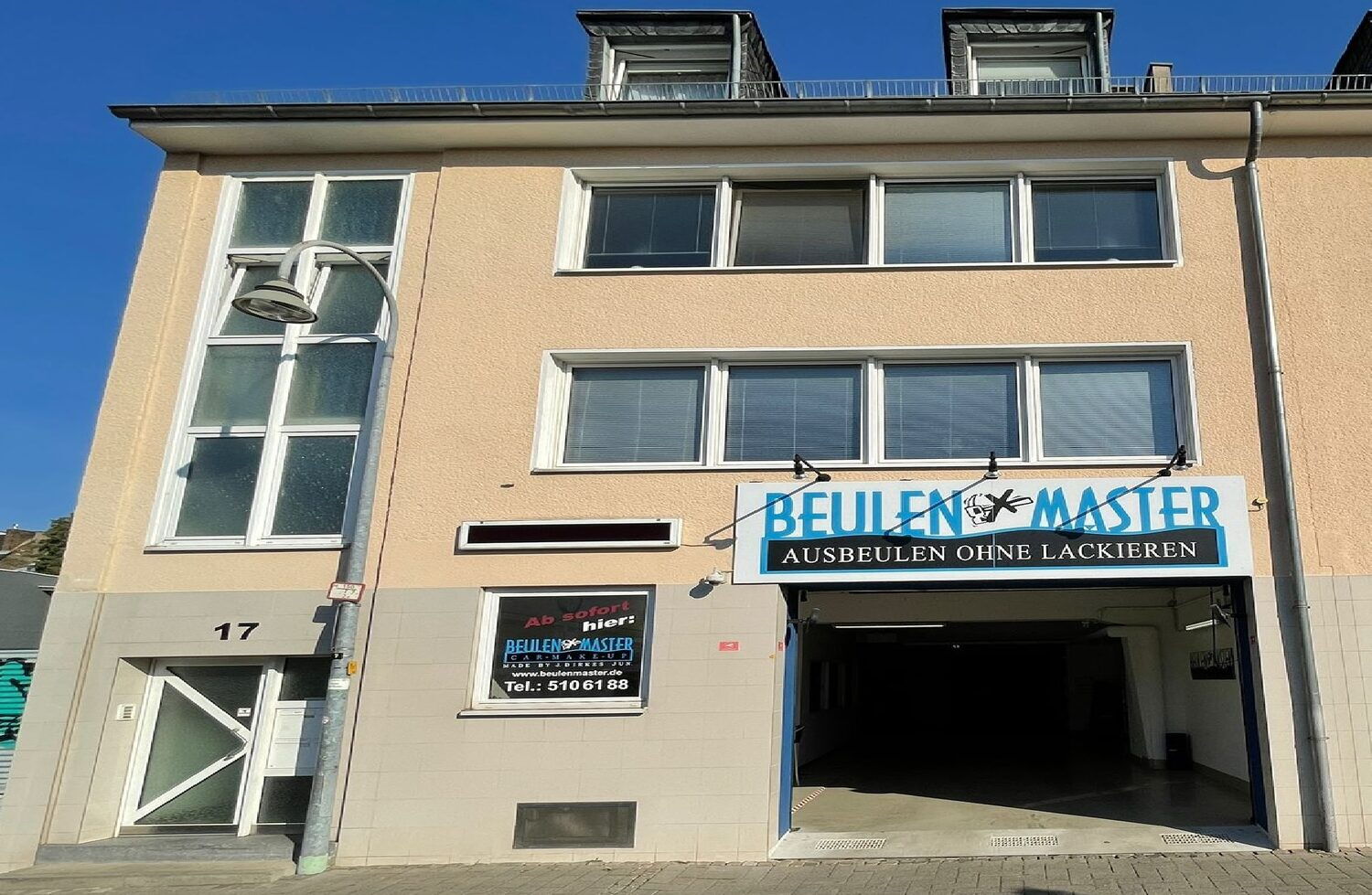 Die Werkstatt am Neptunplatz 17 in Köln mit dem Schild „Ausbeulen ohne Lackieren“